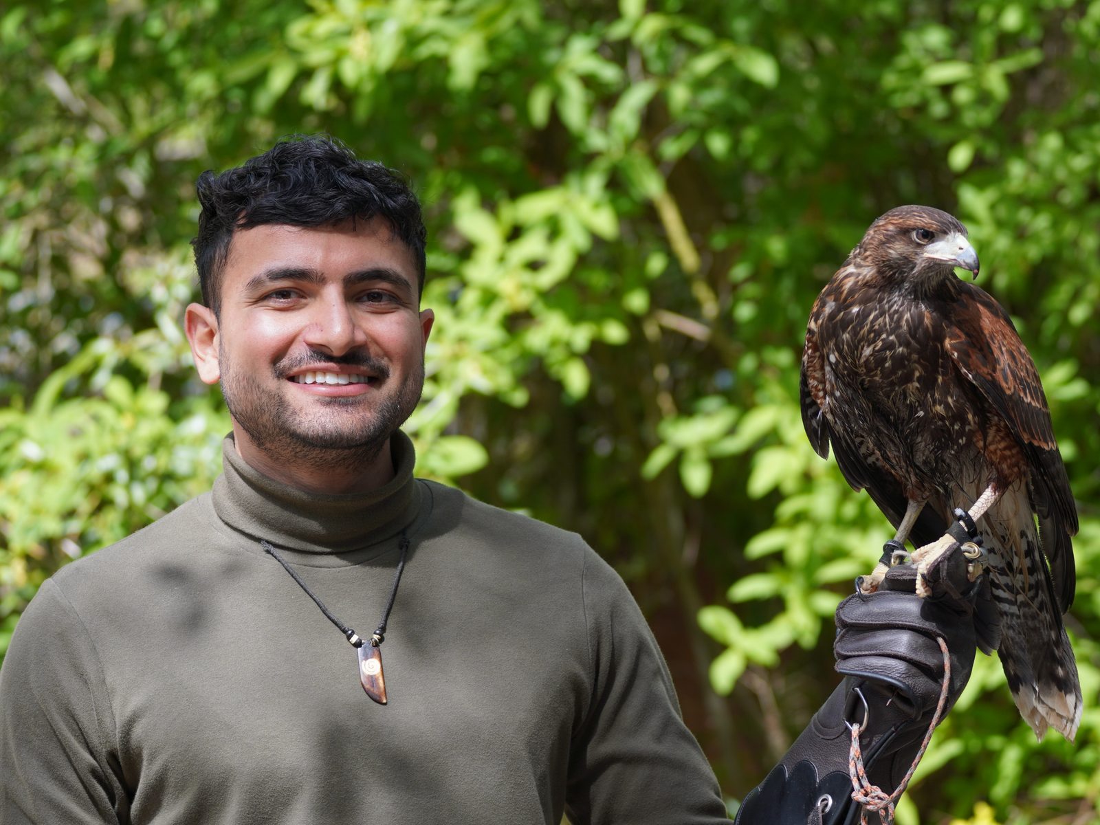 Usman smiling, with a hawk perched on his gloved hand